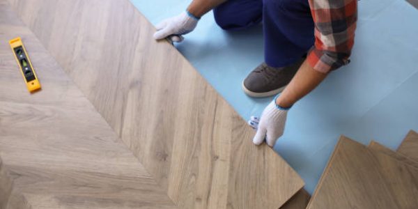 Worker installing laminated wooden floor indoors, closeup Worker installing laminated wooden floor indoors, closeup